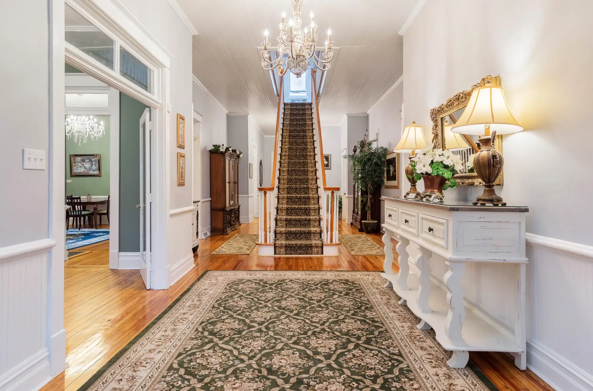 The Magnolia Inn entryway — chandelier, grand staircase, hardwood floors